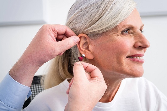 Seniorin bekommt ein Hörgerät eingesetzt, Hörakustik und Hörhilfe für ältere Menschen.